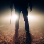 Male Figure Wielding a Crowbar in the Dark with a Car Reflector Background